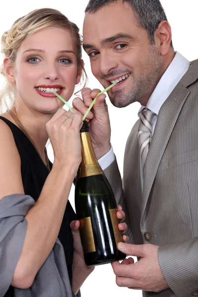 Couple drinking champagne through straw — Stock Photo, Image