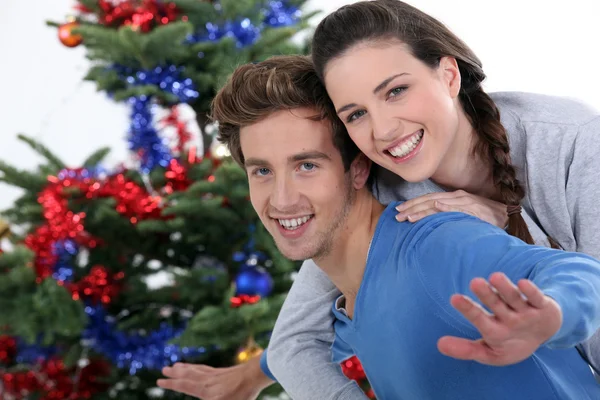 Porträtt av glada unga par poserar nära julgran — Stockfoto