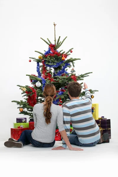 Casal sentou-se na árvore de Natal — Fotografia de Stock