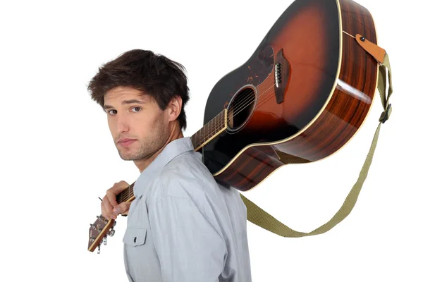 Young man carrying a guitar on his shoulder — Stock Photo, Image
