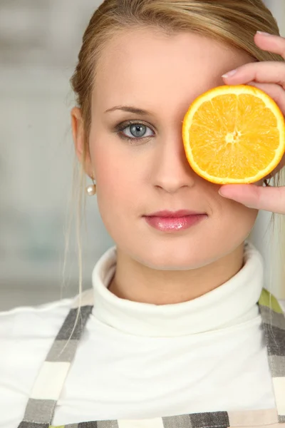 Vrouw die betrekking hebben op haar oog met oranje segment — Stockfoto
