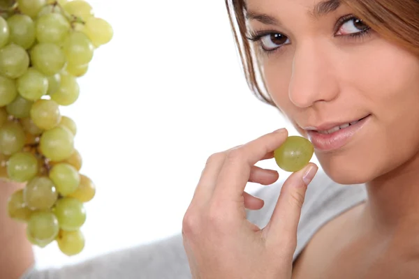 Woman eating green grapes — Stok fotoğraf