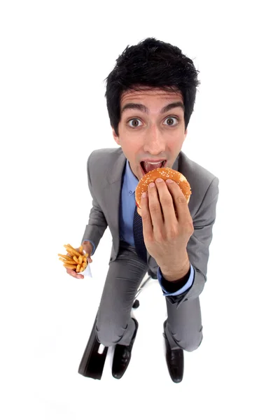 Een zakenman devoring een hamburger. — Stockfoto
