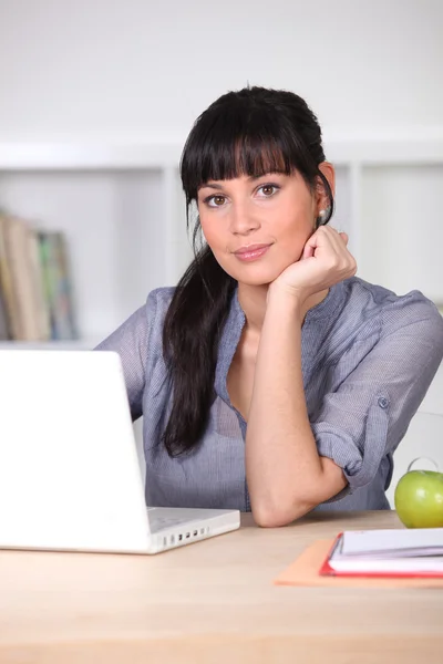 Brunette zat aan bureau met groene appel als een snack — Stockfoto