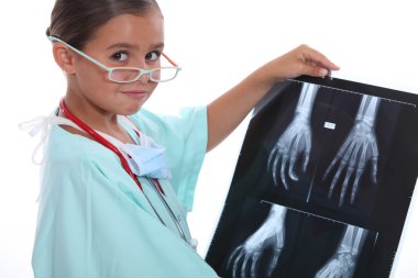 Young girl dressed in hospital scrubs examining an X ray clipart