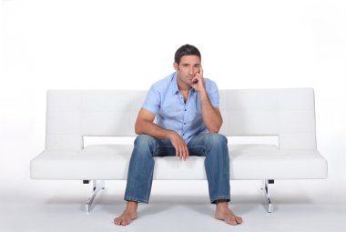 Handsome bloke sitting on sofa clipart