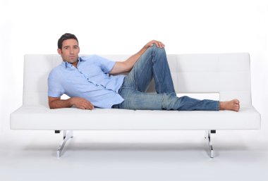 Sulky man lying on a couch clipart