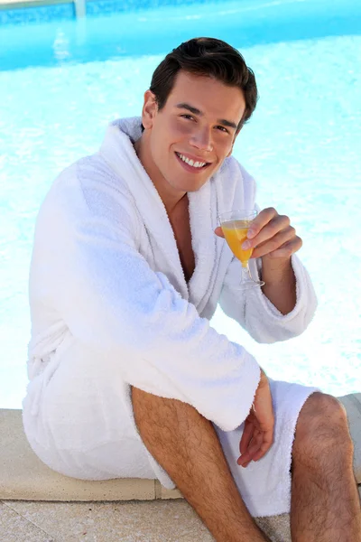 Hombre con jugo en el borde de la piscina — Foto de Stock