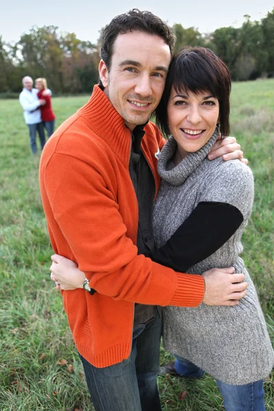 Zwei Paare, die sich auf einem Feld umarmen — Stockfoto