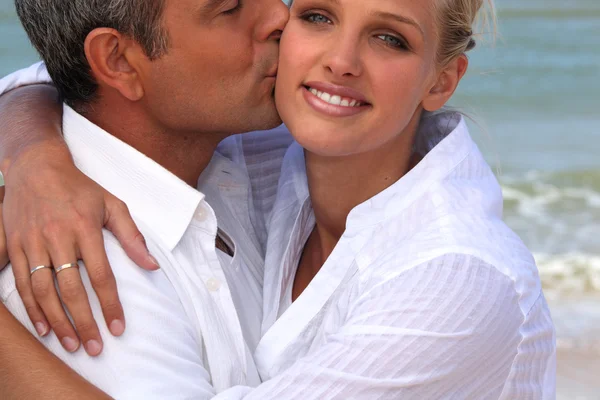 Hombre besando a su novia rubia en la playa — Foto de Stock