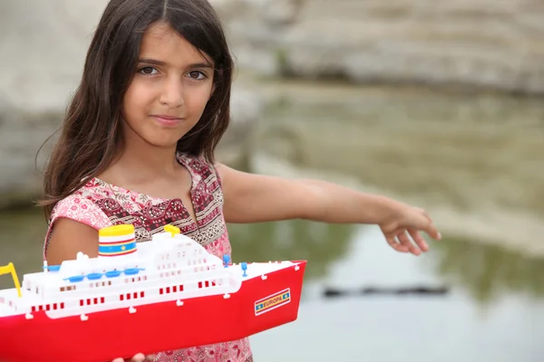 Liten flicka leker med en leksaksbåt — Stockfoto
