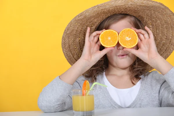 A kislány szeme narancs szeletek elrejtése — Stock Fotó