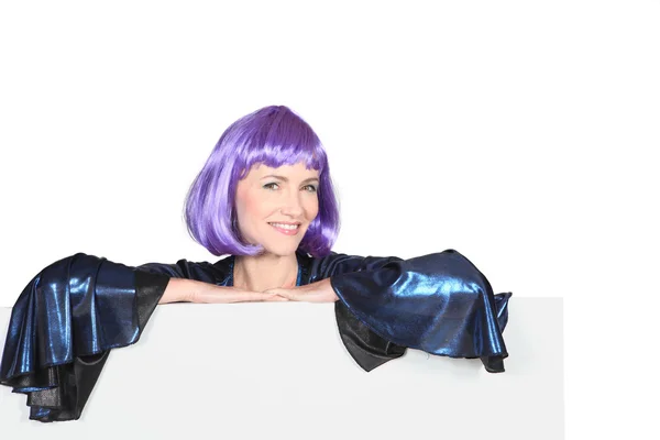 Disco diva in a very shiny purple wig with a board left blank for your message — Stock Photo, Image