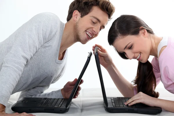 Chica y chico divirtiéndose con sus computadoras en el sofá — Foto de Stock