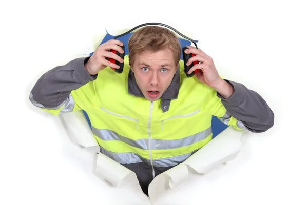 Man with earmuffs emerging from poster — Stock Photo, Image