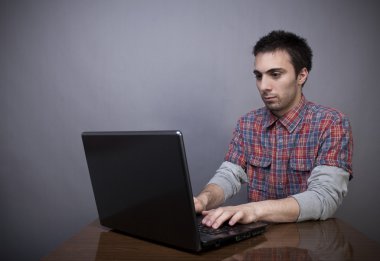 Dizüstü bilgisayarda çalışan genç adam.