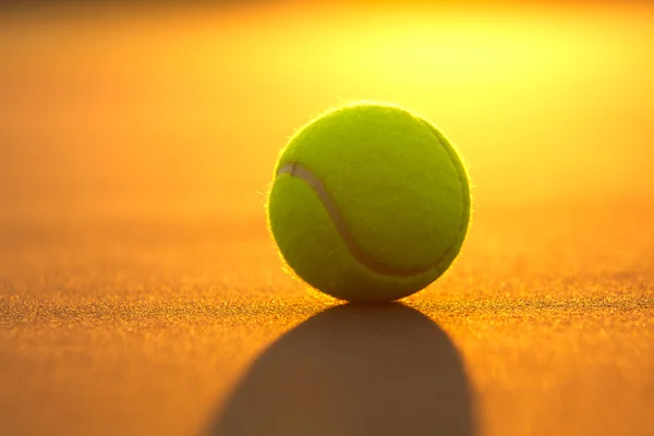 Bola de tênis no tribunal ao pôr do sol — Fotografia de Stock