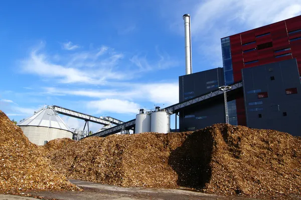 Bio power plant with storage of wooden fuel against blue sky — Stock Photo, Image