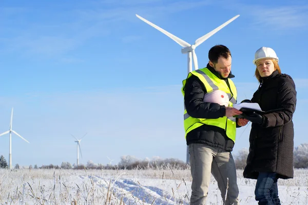 Team of engineers or architects with white safety hat and wind turbines on — Stock Photo, Image