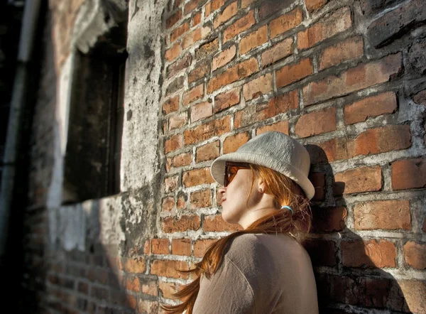 Dreaming pretty woman with white hat in a romantic alley — Stock Photo, Image