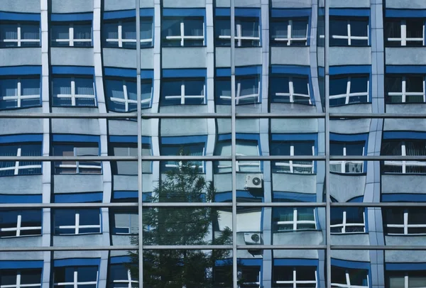 Edificio de oficinas comunista reflejado en ventanas del edificio de oficinas moderno — Foto de Stock