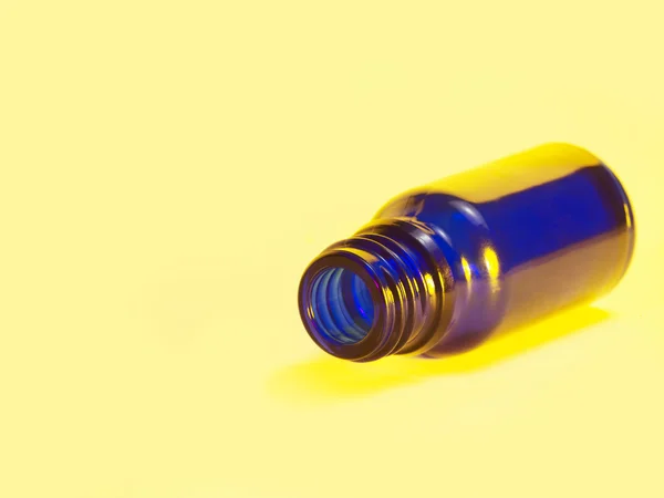 Μικρό μπλε μπουκάλι σε ανοικτό κίτρινο πίσω — Φωτογραφία Αρχείου