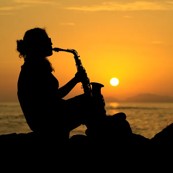 일몰에서 색소폰을 연주 하는 여자 — 스톡 사진