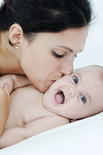 Moeder en dochter spelen gelukkig op witte bed — Stockfoto