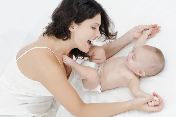 Moeder en dochter spelen gelukkig op witte bed Stockfoto