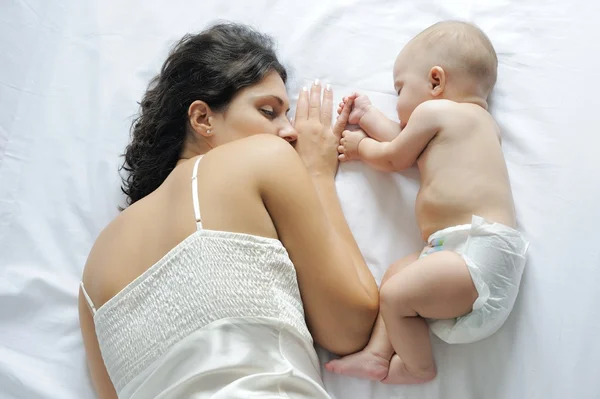 Bambino dormire vicino a sua madre, tenendo il dito Fotografia Stock