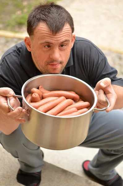 Down syndrome man with sausage — Stock Photo, Image