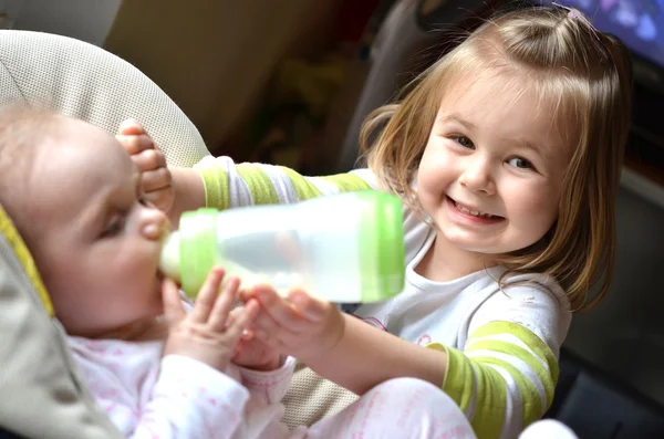 Genç kız bebek kardeşi bir sandalyesi beslenir. — Stok fotoğraf