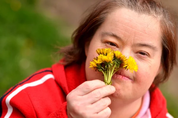 Down syndrome woman blowing dandelion — Stock Photo, Image