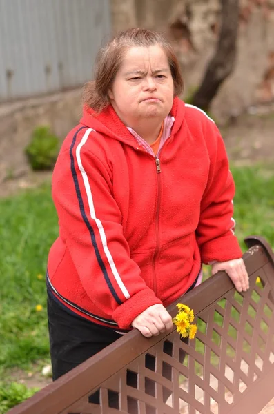 Down syndrome woman blowing dandelion — Stock Photo, Image