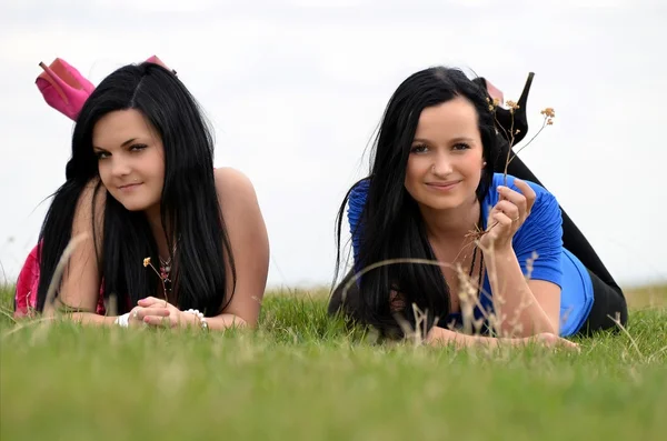 Zwei junge schöne Mädchen, die auf einem grünen Hintergrund liegen — Stockfoto