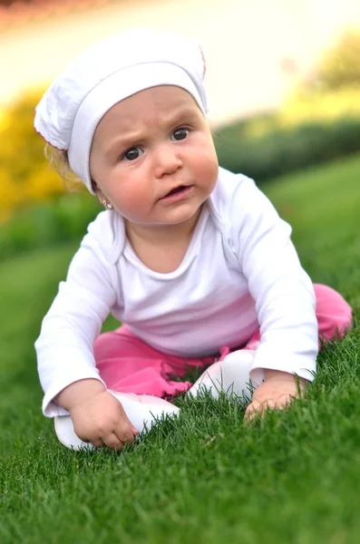 Счастливый ребенок, сидящий на траве — стоковое фото