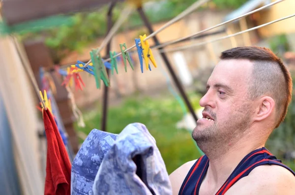 Человек с синдромом Дауна вешает одежду — стоковое фото