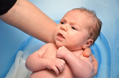 Yeni doğan bebek anne tarafından mavi küvet banyo