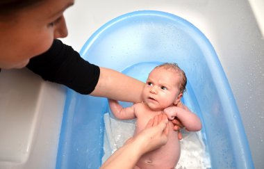 Yeni doğan bebek anne tarafından mavi küvet banyo