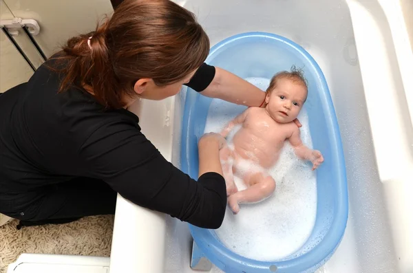 Baño de bebé recién nacido en bañera azul por madre — Foto de Stock