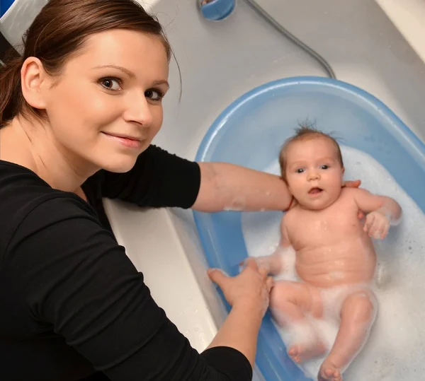 Banho de bebê recém-nascido na banheira azul pela mãe — Fotografia de Stock