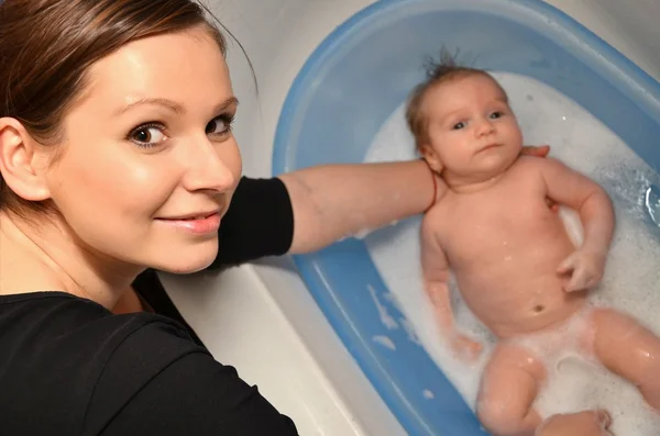 Yeni doğan bebek anne tarafından mavi küvet banyo — Stok fotoğraf