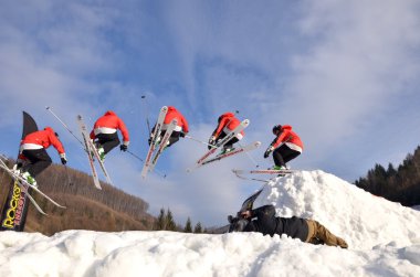 Güneşli bir günde yüksek dağlara atlayan snowboardcu..