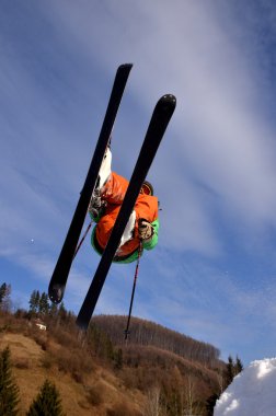 Güneşli bir günde yüksek dağlara atlayan snowboardcu..