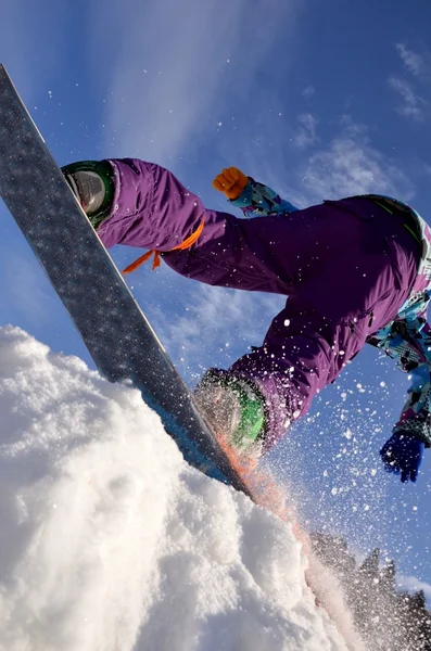 Snowboardåkare hoppar i höga berg på solig dag. — Stockfoto