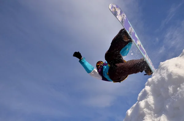 Snowboarder beim Sprung in hohe Berge bei sonnigem Tag. — Stockfoto