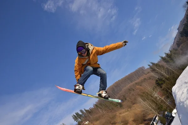 Lumilautailija hyppäämässä korkeilla vuorilla aurinkoisena päivänä. — kuvapankkivalokuva