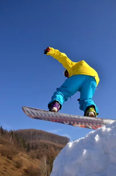 Snowboarder at jump inhigh mountains at sunny day. — Stock Photo, Image