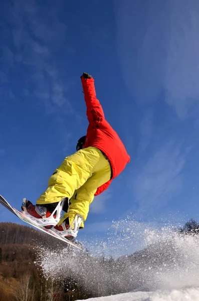 Snowboardåkare hoppar i höga berg på solig dag. — Stockfoto