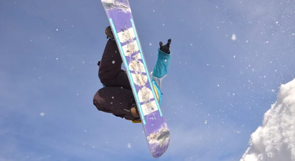 Snowboardzista podczas skoku w wysokie góry w słoneczny dzień. — Zdjęcie stockowe